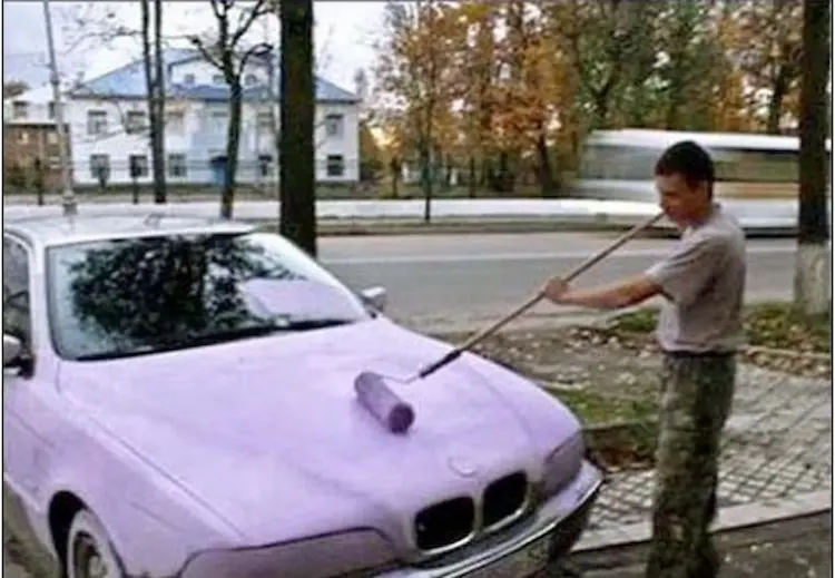 Picture of a man apinting his car with a roller
