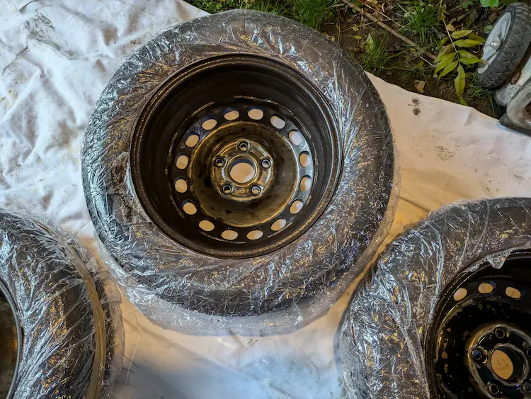 Steel wheels laid out in a makeshift DIY paint booth